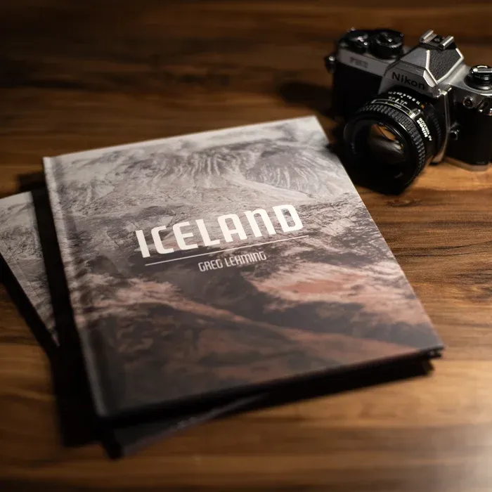 A photo of the hardcover photo book Iceland by Greg Lehming next to a camera on a wooden surface